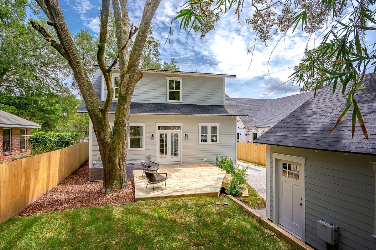 House plan exterior: Two-story home with light blue siding, double doors, deck, and detached garage.