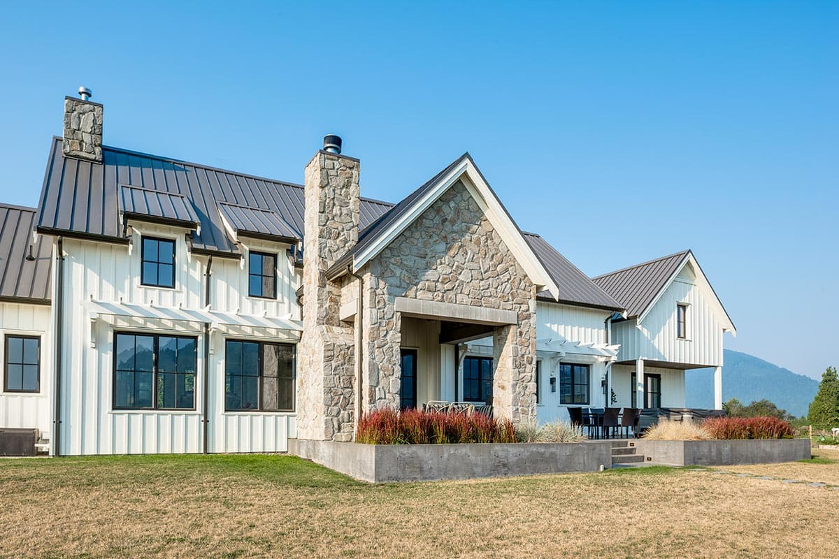 Modern Farmhouse house plan exterior with white board and batten siding, stone accents, metal roof, and multiple gables.