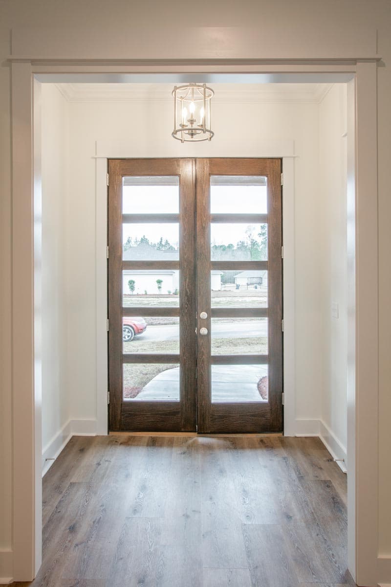 Entrance interior with double glass doors, modern lantern fixture, and wood-look flooring.
