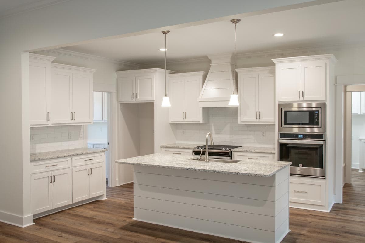 Contemporary kitchen with white shaker cabinets, granite countertops, large island with sink, and stainless steel appliances.