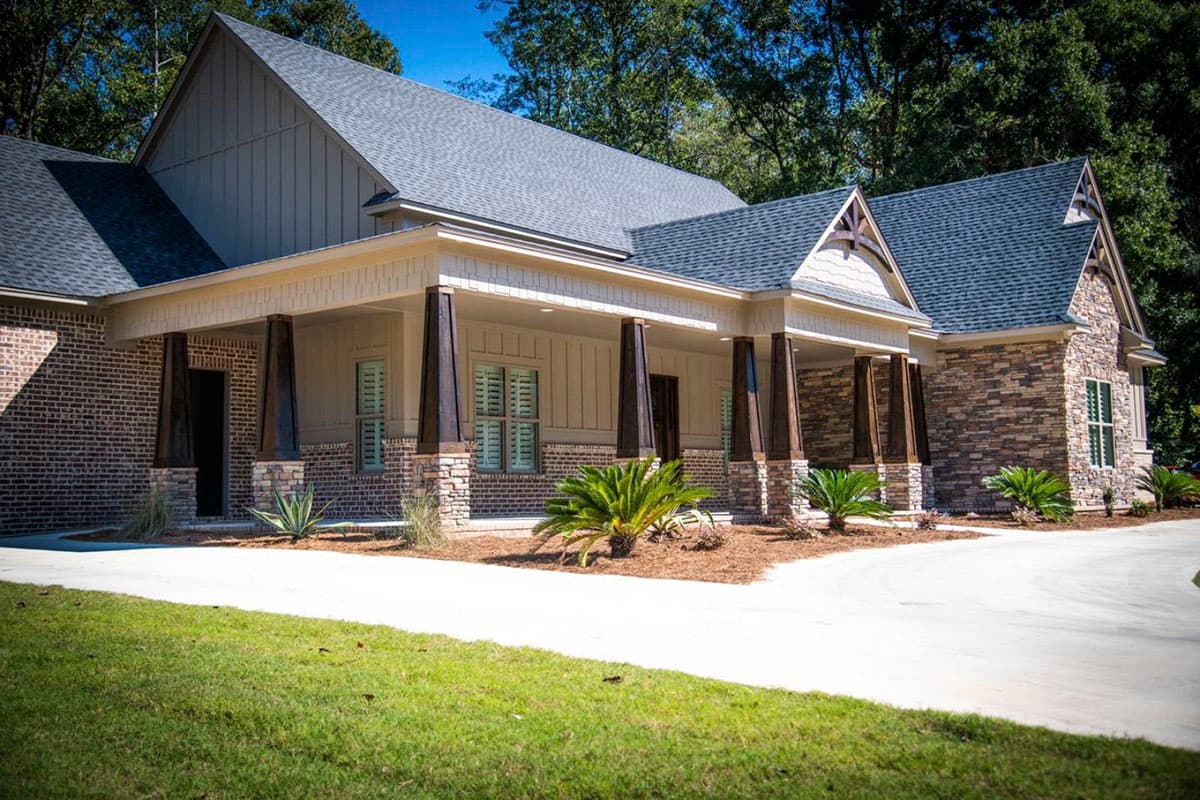 House plan exterior: One-story Modern Farmhouse with brick and stone facade, covered porch with wood columns, and gabled dormers.