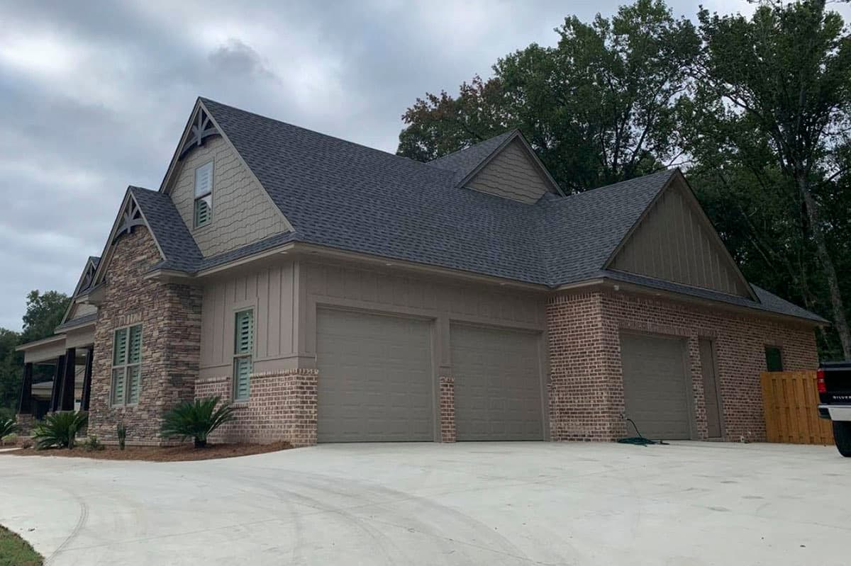House plan exterior with stone and brick facade, multiple gables, and a four-car garage.