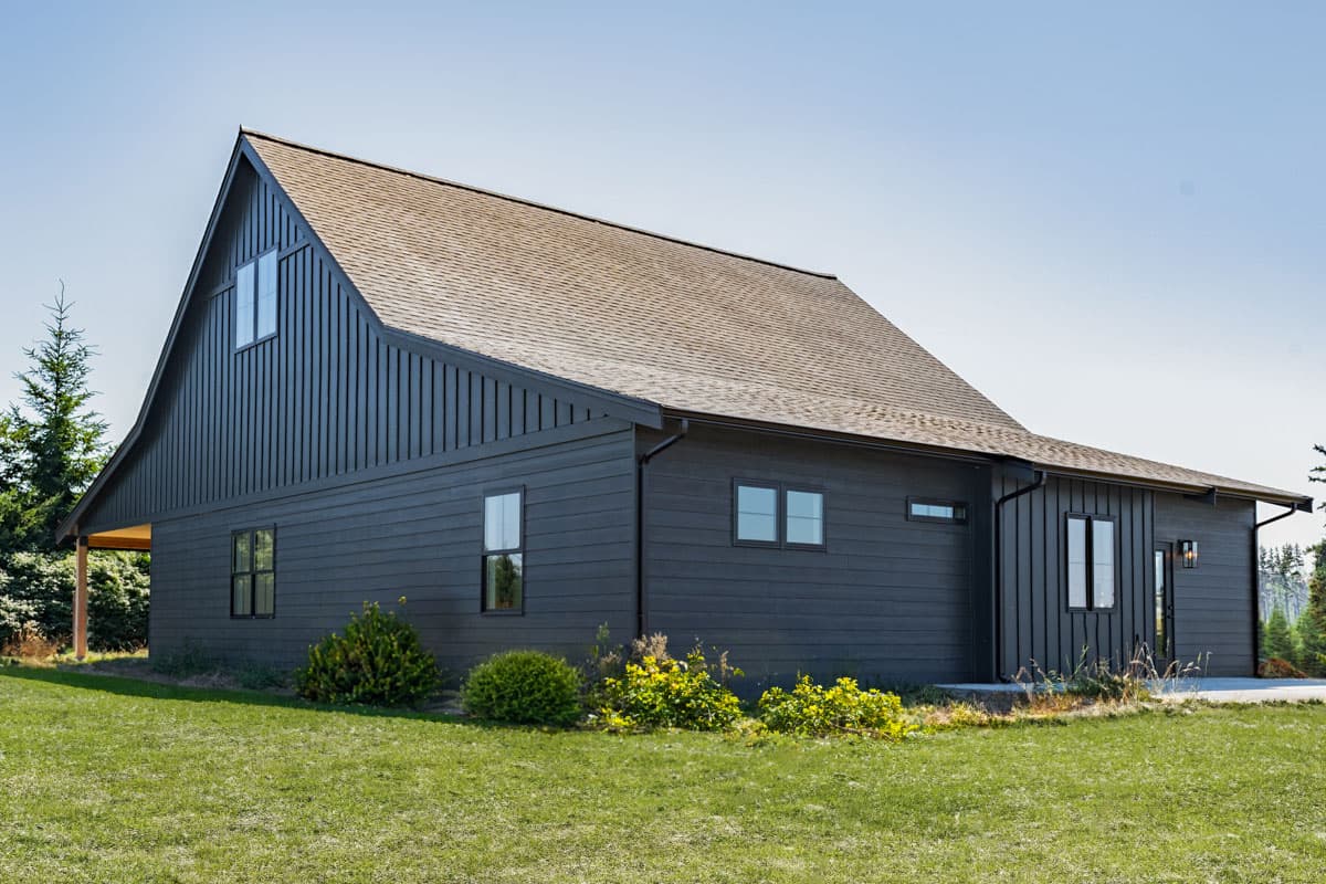 House plan exterior: Modern style, gambrel roof, dark vertical and horizontal siding, multiple windows.