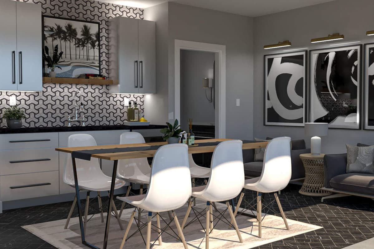 Dining area with white chairs at a wooden table, adjacent to a kitchen with gray cabinets and geometric tile backsplash.