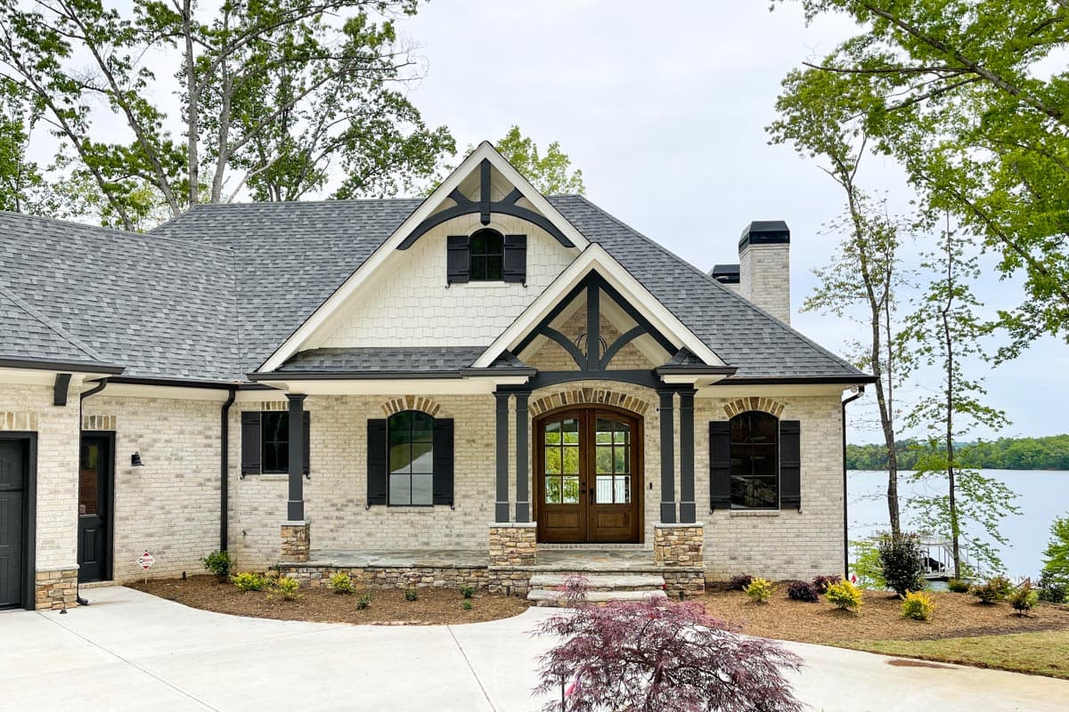 House plan exterior: Two-story Modern Farmhouse with brick and shake siding, exposed rafter tails, and a stone-clad porch.