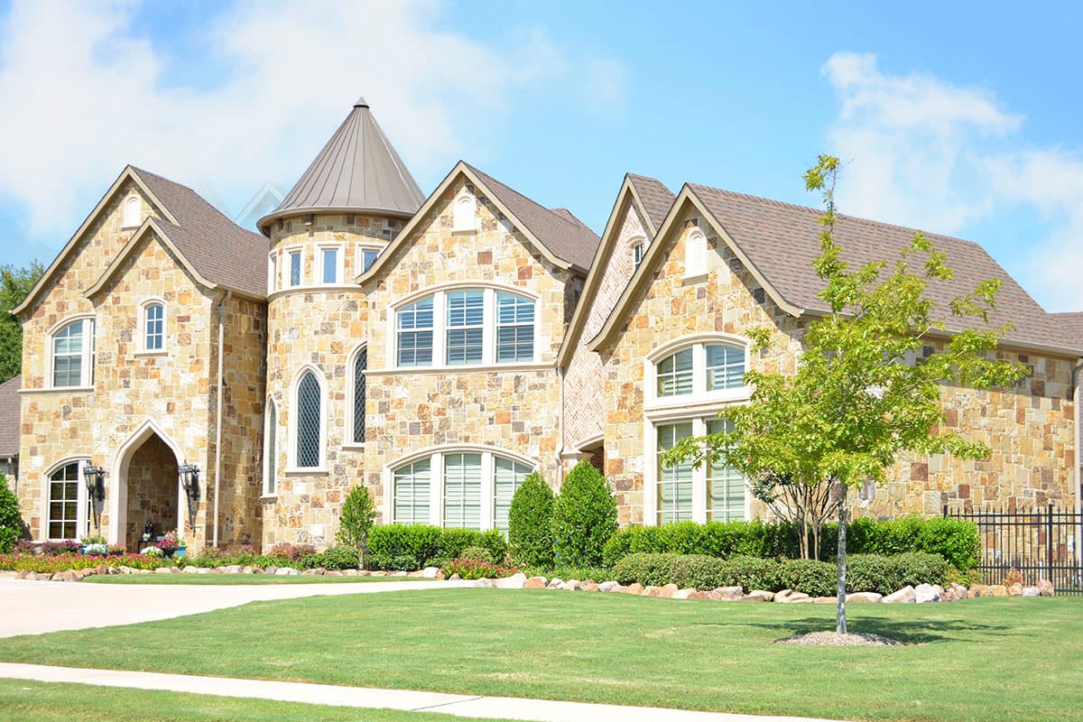 House plan exterior. Two-story stone home with turrets, arched gables, and prominent dormers.