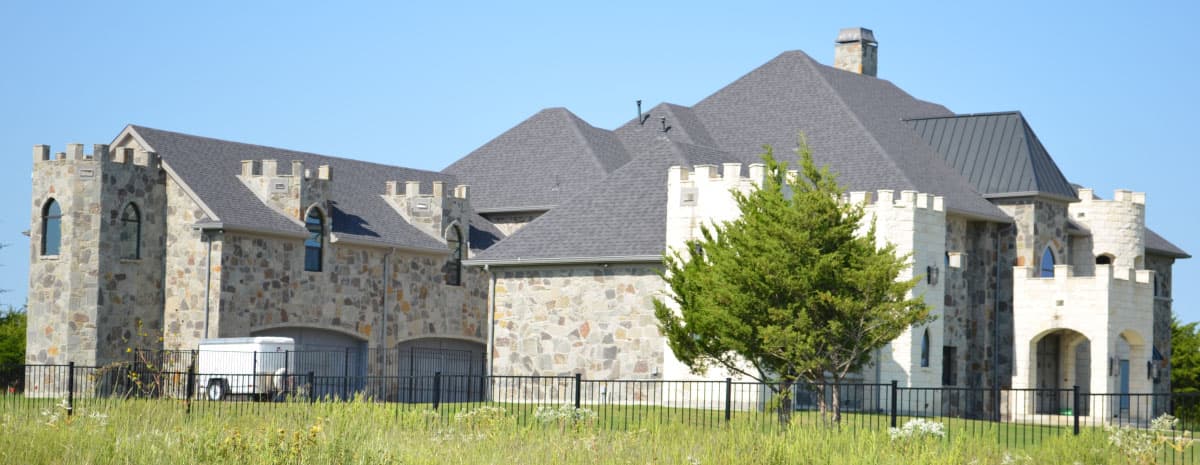 Castle-style house plan exterior with stone facade, turrets, arched windows, multiple gables, and a three-car garage.