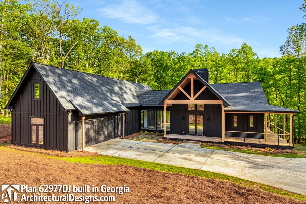 Modern farmhouse exterior with dark vertical siding, gable roof, covered porch, and attached garage.