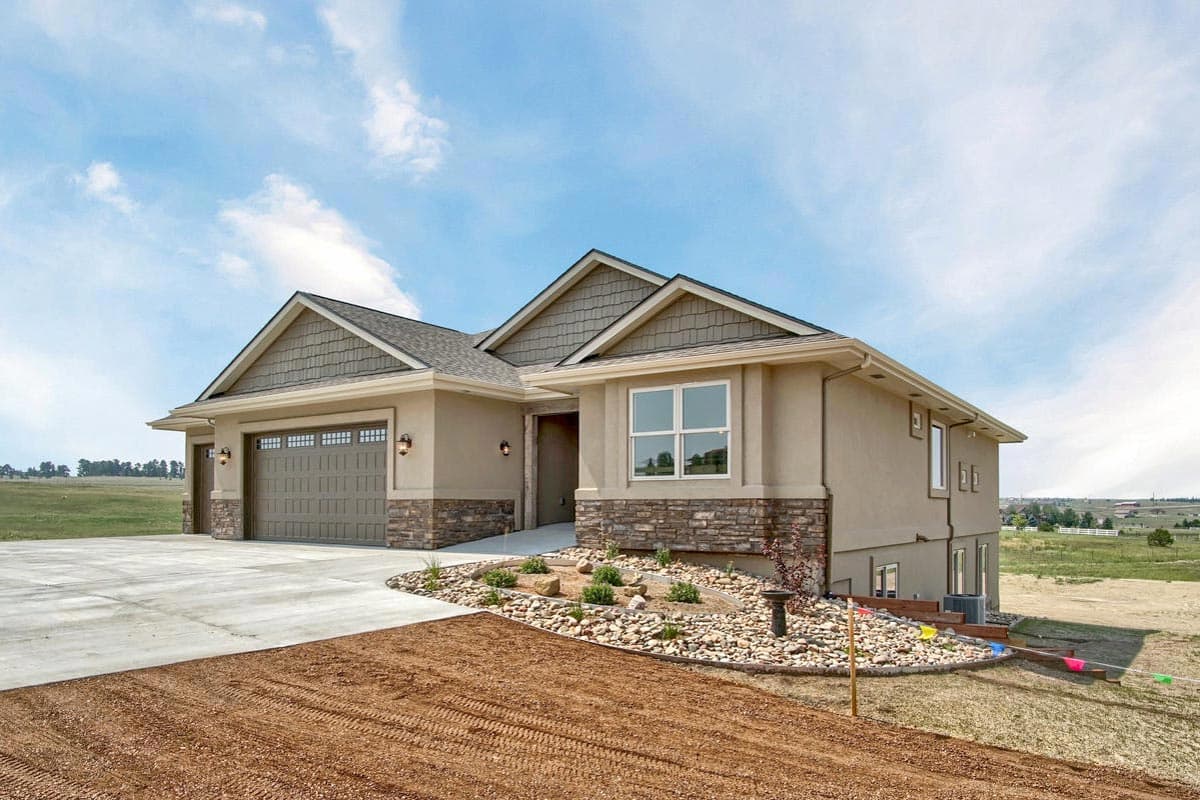 House plan exterior: Ranch style, three-car garage, prominent gables with shake siding, stone accents.