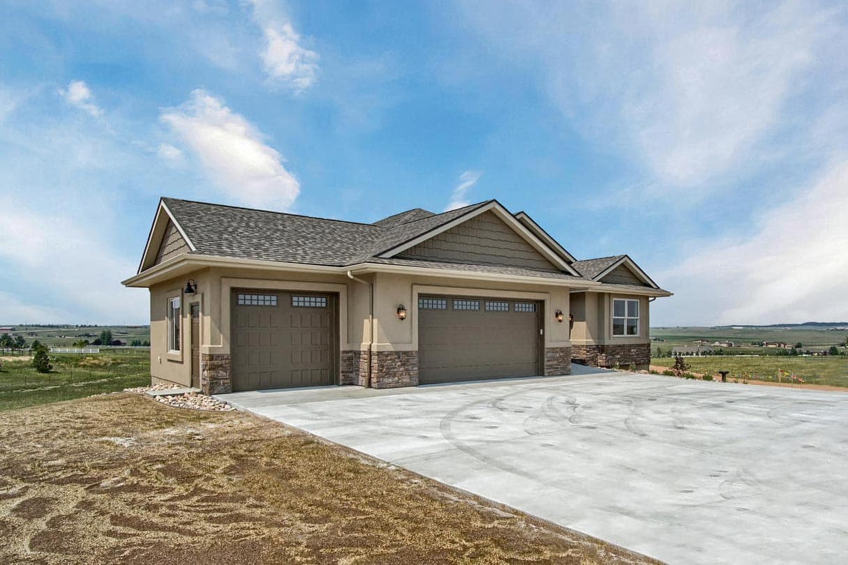 Ranch-style house plan exterior with a three-car garage, stone accents, and prominent gables.