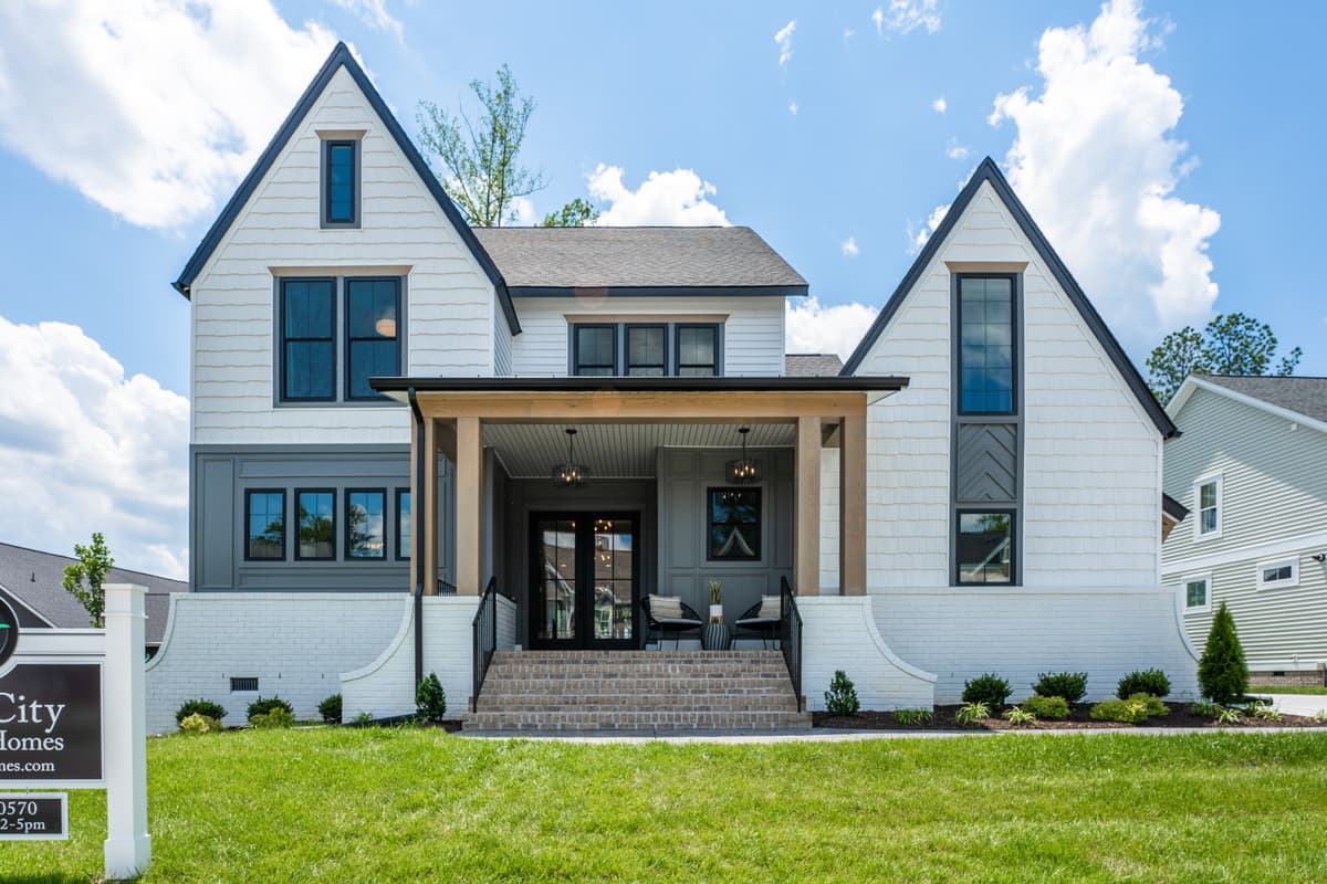 House plan exterior. Two-story Modern Farmhouse with gables, a covered porch, and a brick-based foundation.