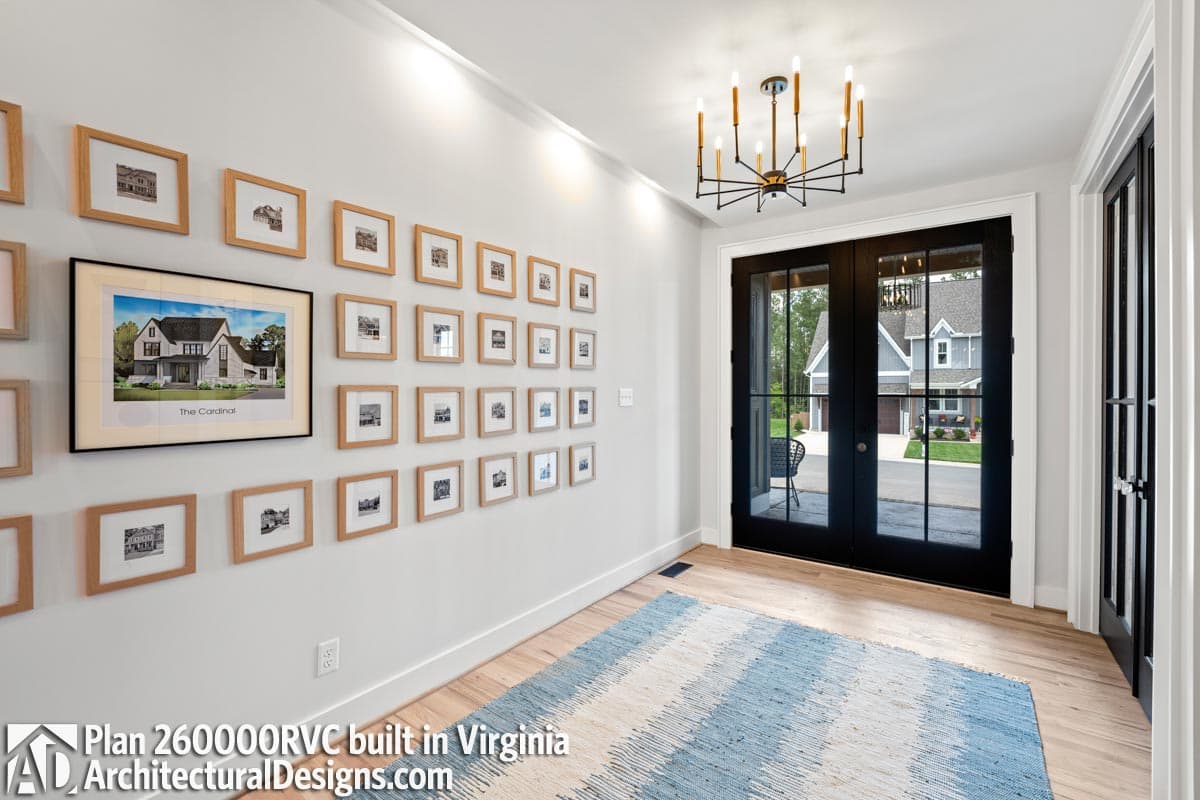 Hallway with framed house plan art and double glass doors opening to a residential exterior.