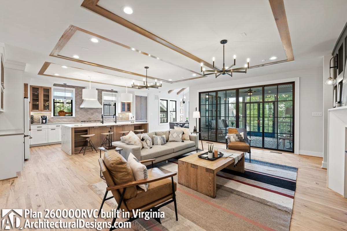 Open-concept living space with kitchen island, comfortable seating, and large metal-framed glass doors leading to an outdoor area.
