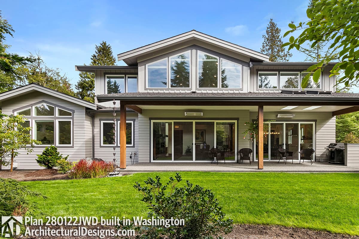 Modern house plan exterior with a covered patio, large windows, and a prominent gable with triangular windows.