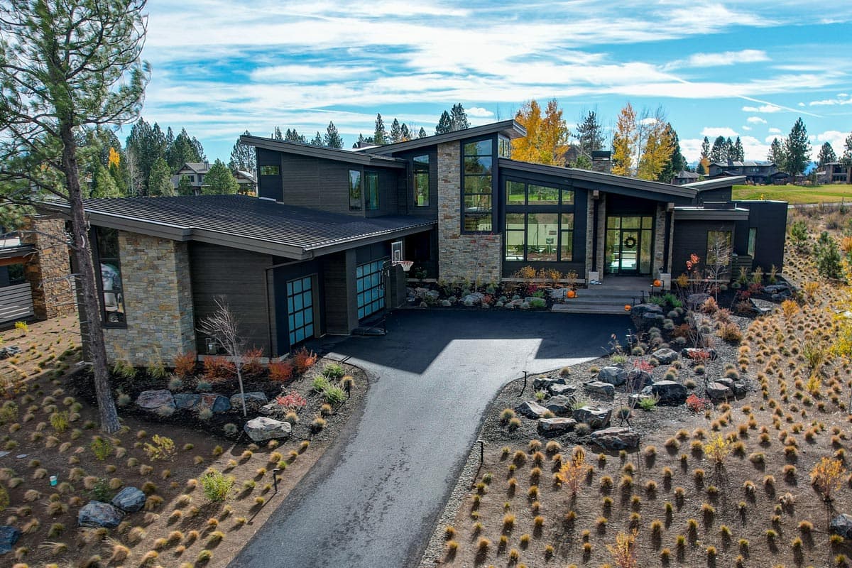 Modern house plan exterior with angled rooflines, stone and wood siding, large windows, and a two-car garage.