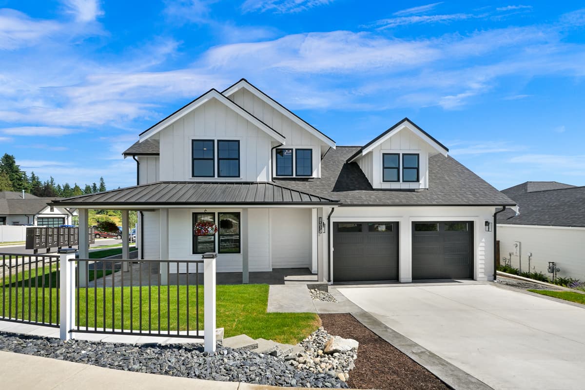 House plan exterior. Two-story Modern Farmhouse with a covered porch, gabled roofline, and attached two-car garage.