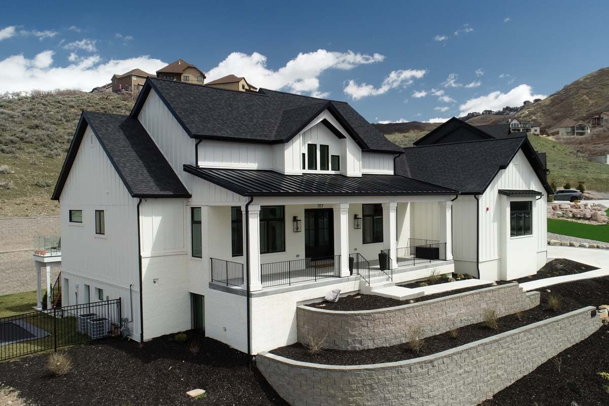 Modern Farmhouse house plan exterior with white board and batten siding, black metal roof, and a covered front porch supported by columns.