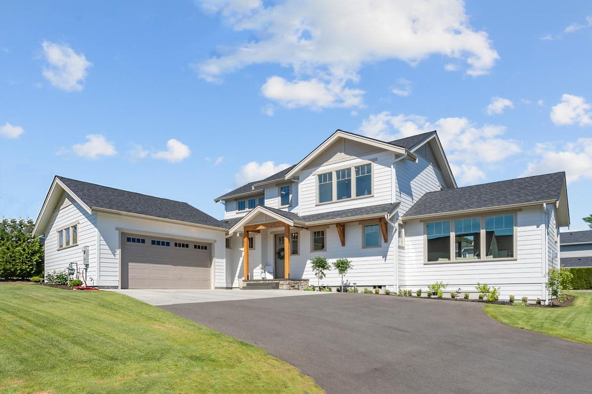 House plan exterior. Two-story Modern Farmhouse with gabled rooflines, a front porch with wooden supports, and attached garage.