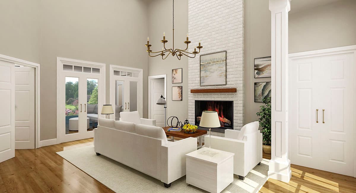 Great room with vaulted ceiling, white brick fireplace, and double doors opening to an outdoor patio.