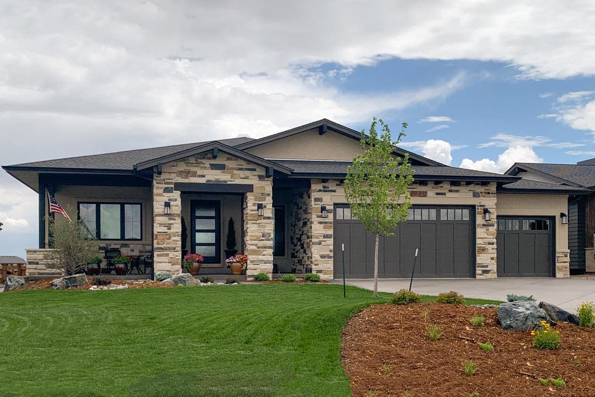 House plan exterior with stone veneer, flat roof, and two garage doors. The entry has a porch and the home has a modern style.
