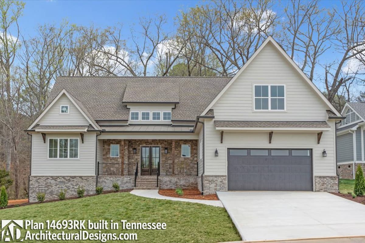 Modern Farmhouse style house plan exterior with stone accents, large front porch, dormers, and side-entry garage.