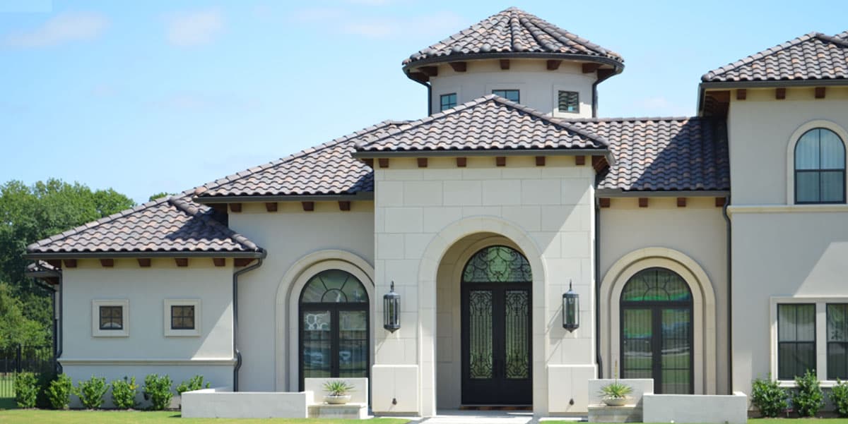 Mediterranean style house plan exterior with tiled roof, arched entryway, double doors, and decorative windows.