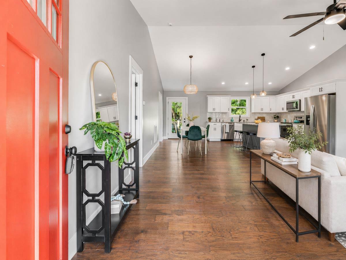 Interior view of open-concept living space with vaulted ceiling, kitchen island, and dining area.