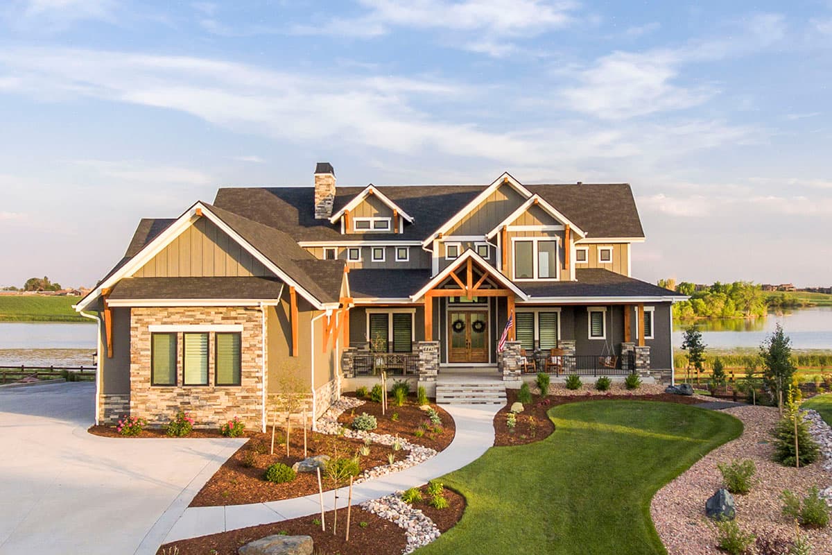 House plan exterior with Craftsman style, two stories, front-facing gables, covered porch with columns, and stone accents.