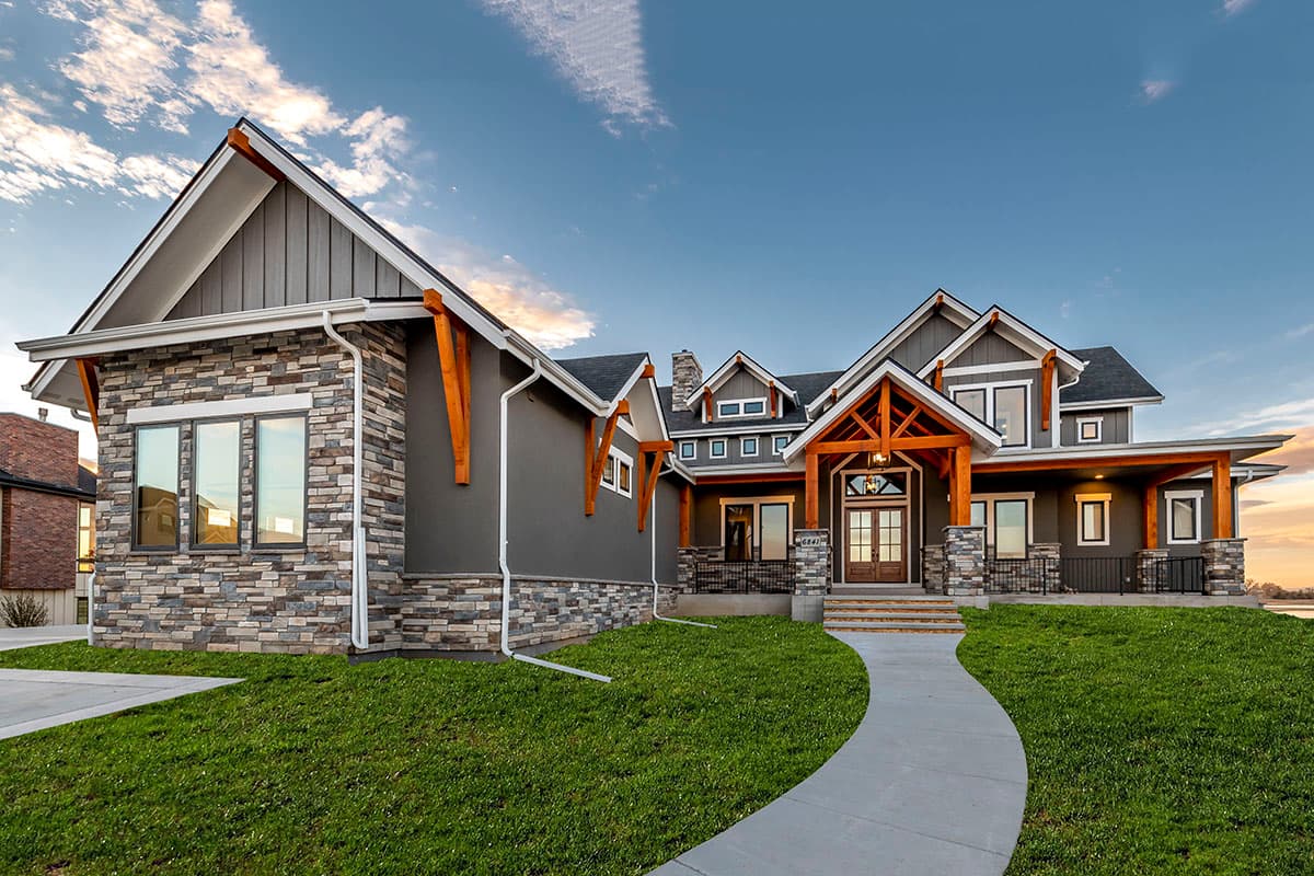 House plan exterior: Modern Craftsman style, two stories, stone and siding, prominent gables with exposed wood beams, and covered front porch.