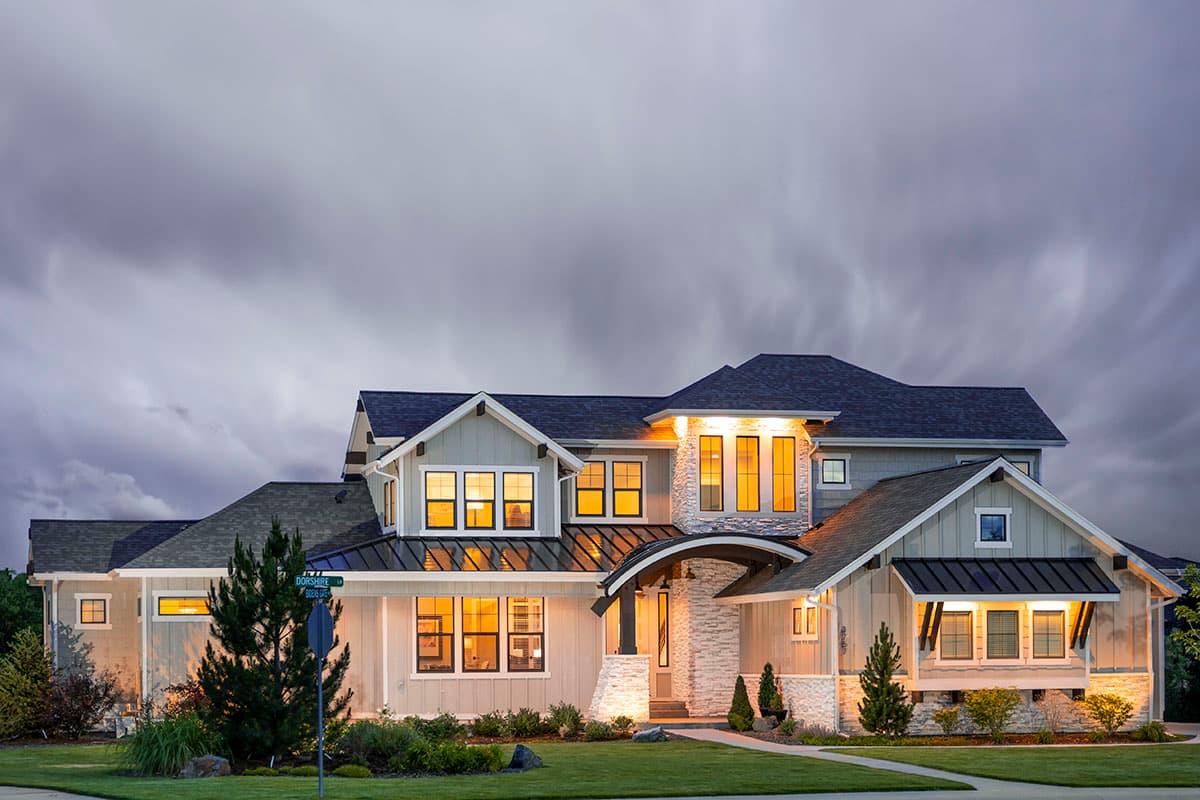 House plan exterior. Two-story Modern Farmhouse with gables, a covered entry, and various window styles. Stone accent on the facade.