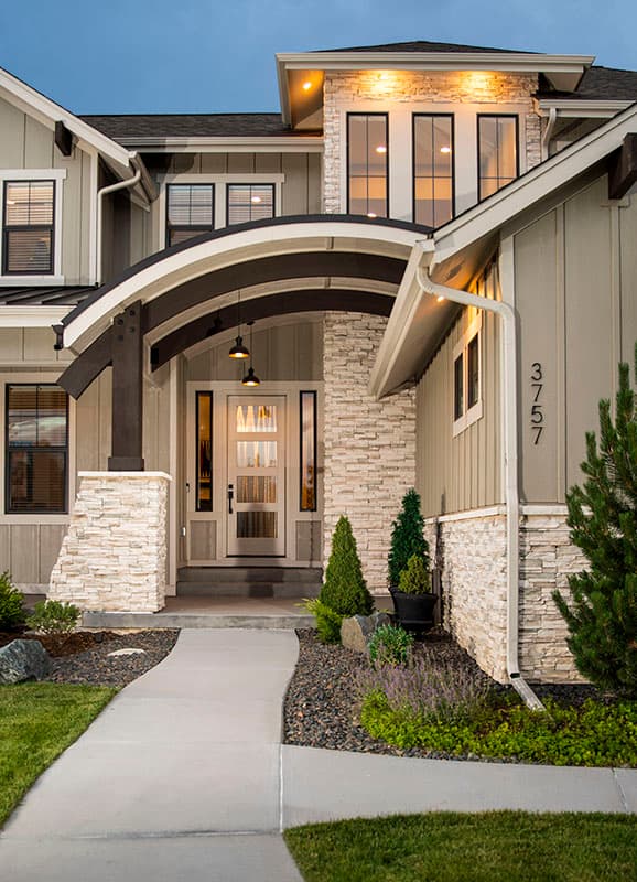House plan exterior with stone accents, a covered entryway with a curved beam, and multiple windows.