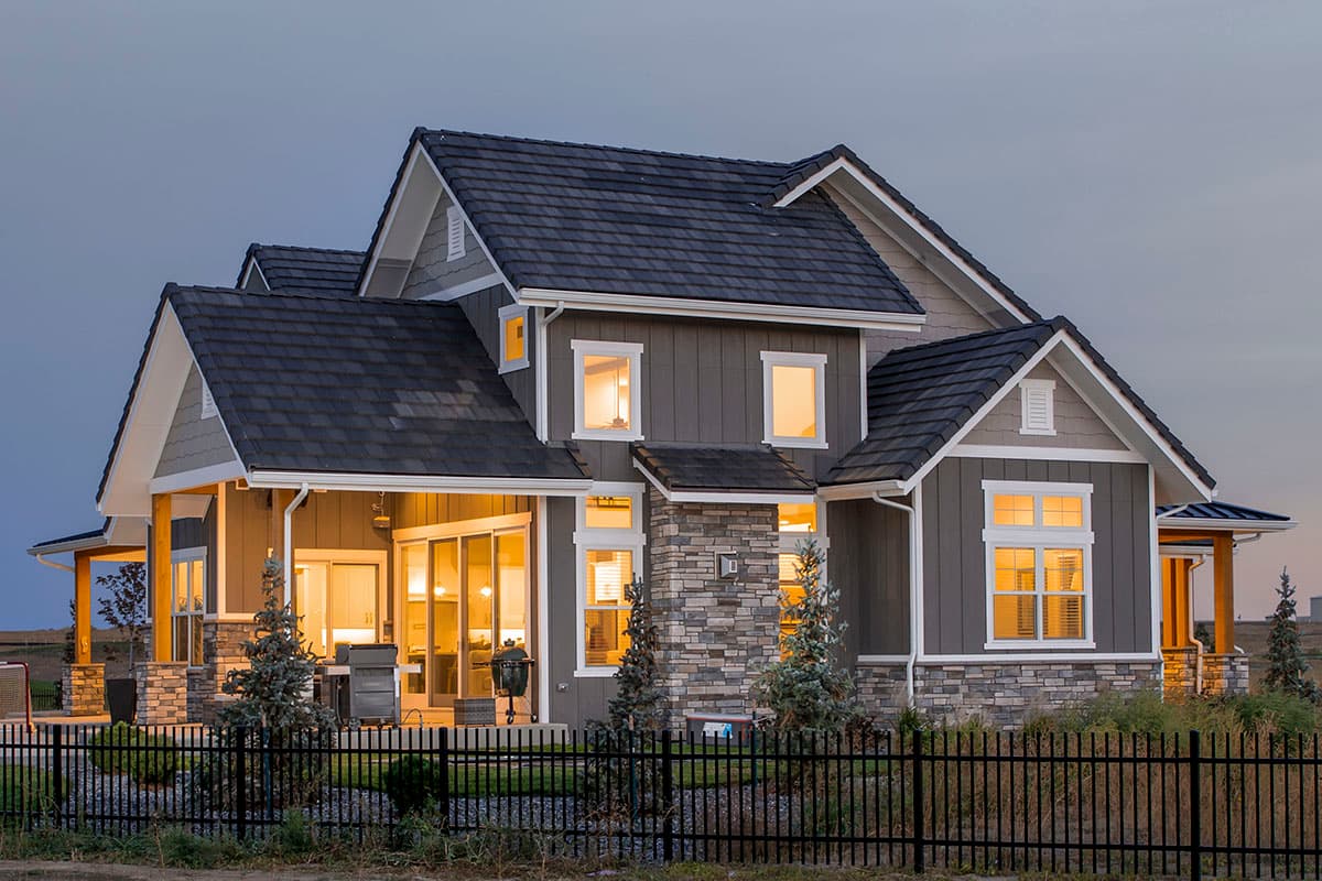 House plan exterior: Two-story home with multiple gables, stone accents, covered patio, and a dark shingle roof.