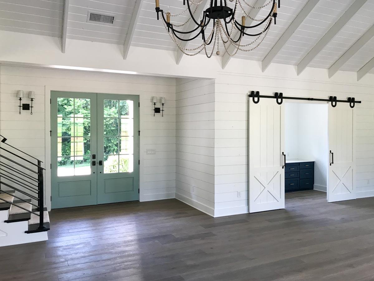 Interior view: Great room with shiplap walls, vaulted ceiling, French doors, barn doors, and stairs.