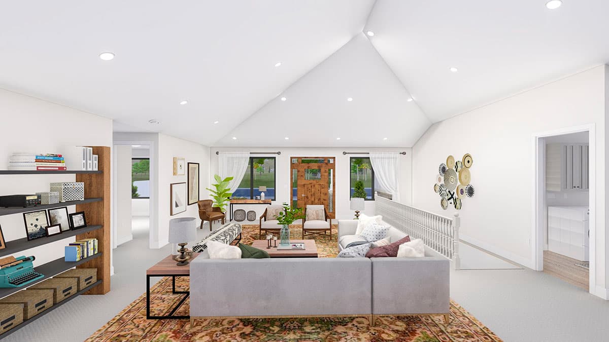 Great room with vaulted ceiling, natural wood front doors, sectional sofa, and decorative wall art. Visible staircase and doorway to laundry.