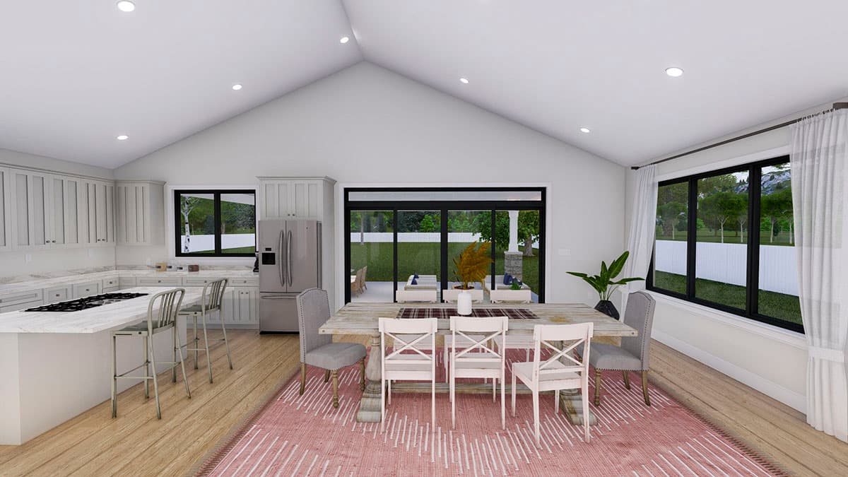Open-concept kitchen and dining area with vaulted ceiling, large windows, and sliding glass doors to patio.