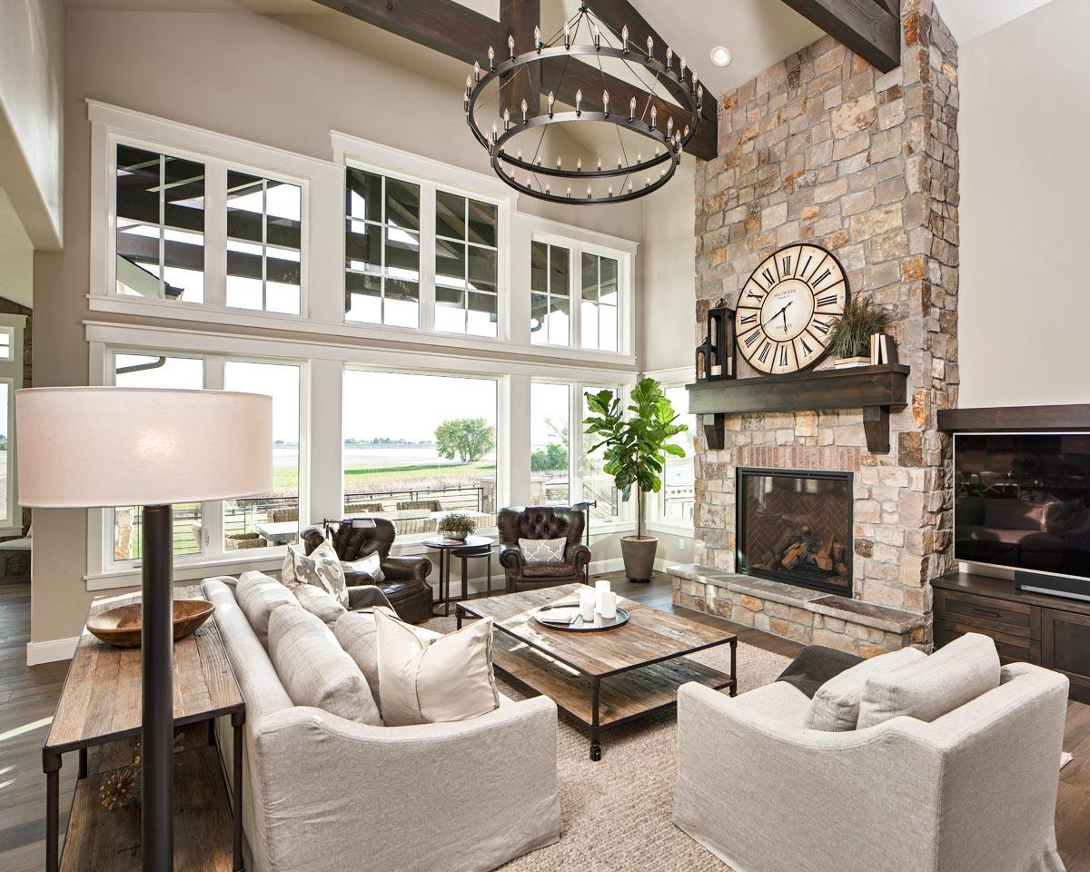 Great room with vaulted beamed ceiling, large stone fireplace, and wall of windows. House plan interior.