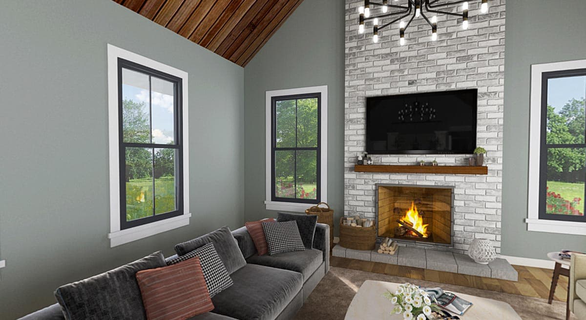 Interior view of a living room with a vaulted wood-paneled ceiling, fireplace with TV above, and large windows.