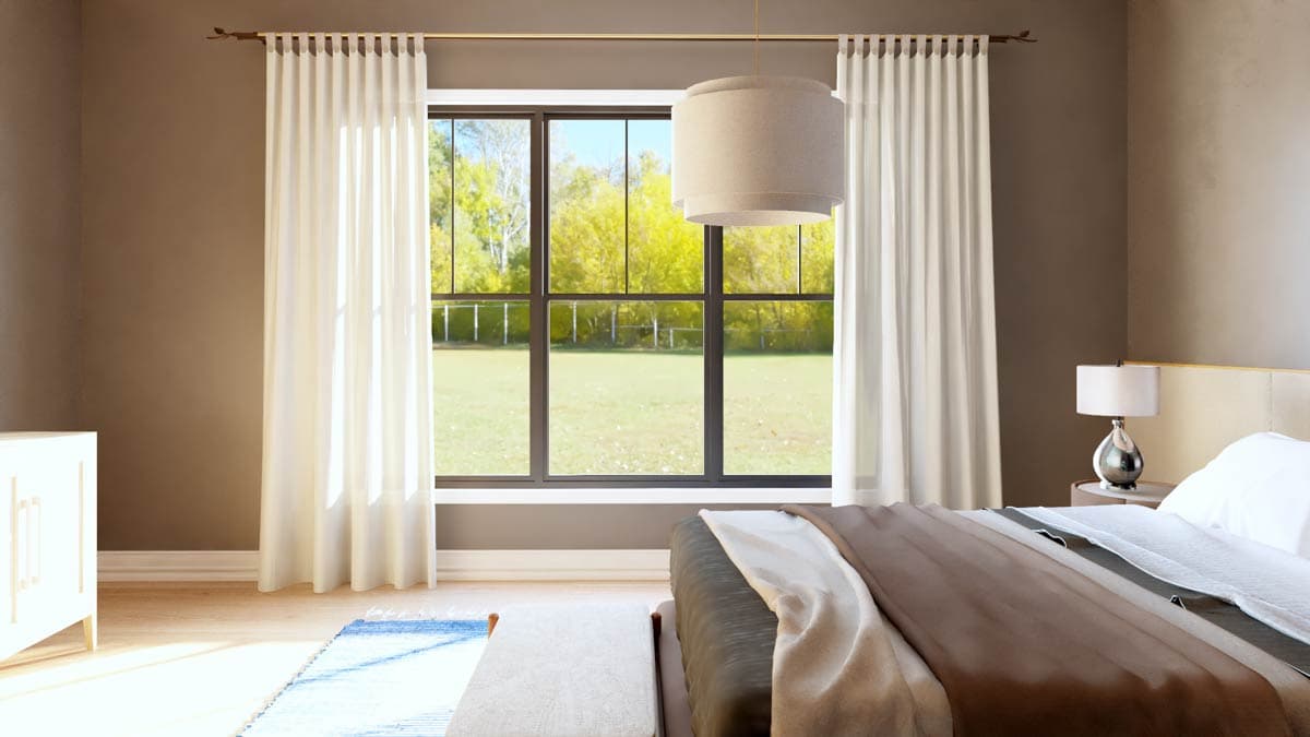 Bedroom interior with large multi-pane window, white drapes, pendant light, and unmade bed.