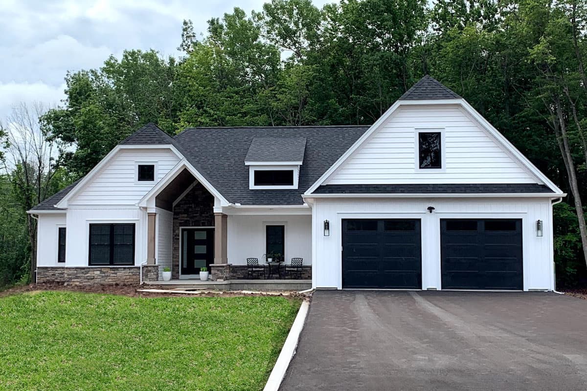 House plan exterior. Two-story Modern Farmhouse with gables, stone accents, and a two-car garage. Porch and dormer included.