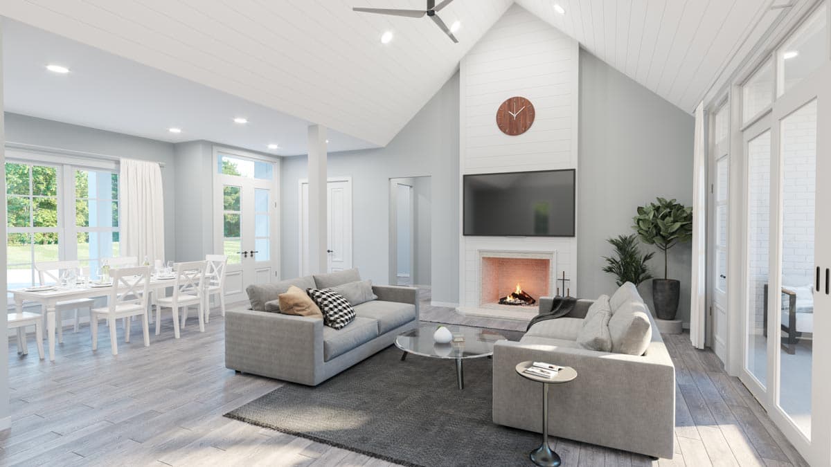 Living room with vaulted ceiling, fireplace, wall-mounted TV, dining area, and large windows.