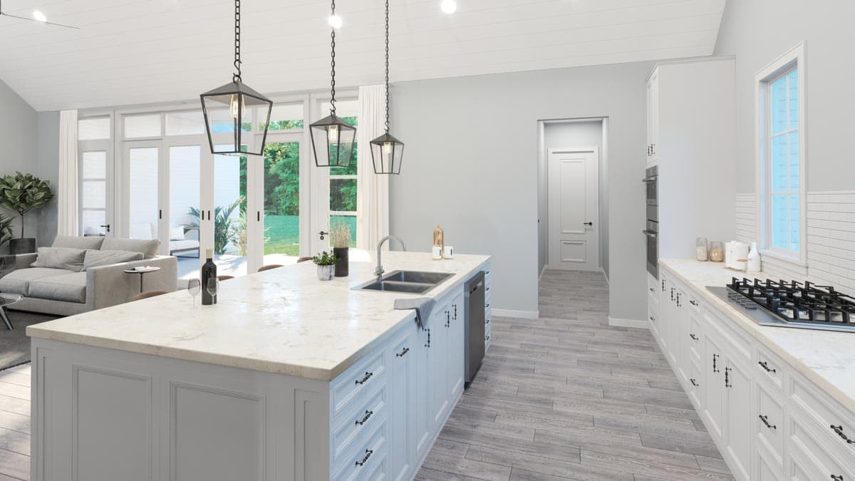 Kitchen with large island, double oven, gas range, and vaulted ceiling. Opens to living area with large glass doors.