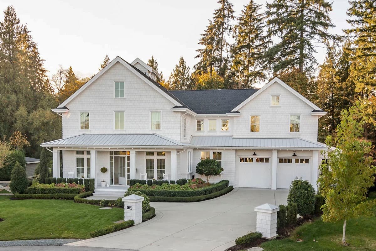 House plan exterior: white Modern Farmhouse with metal roof porch, gabled dormers, and a three-car garage.