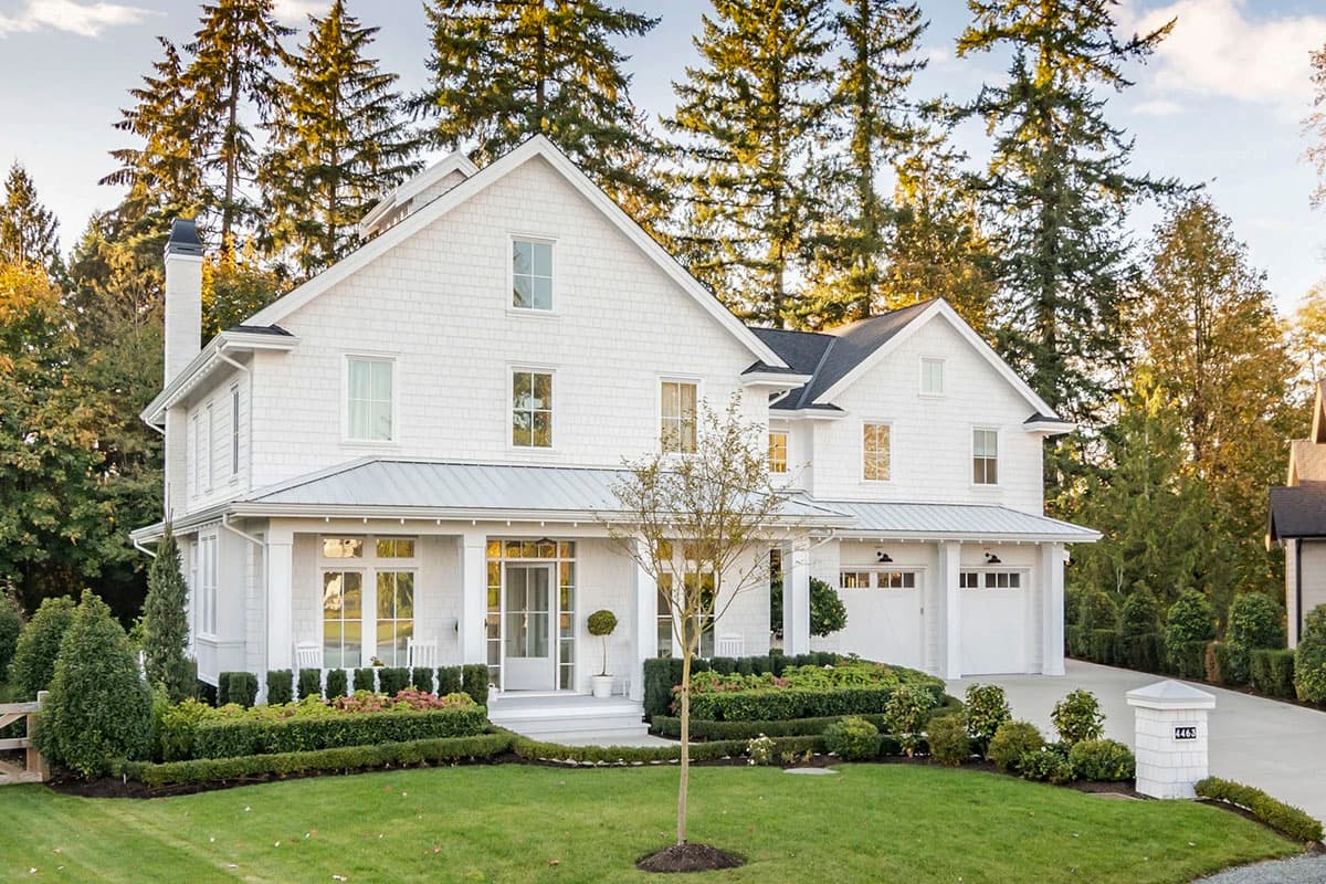 Modern Farmhouse style house plan exterior with two stories, a wraparound porch, gables, and a three-car garage.