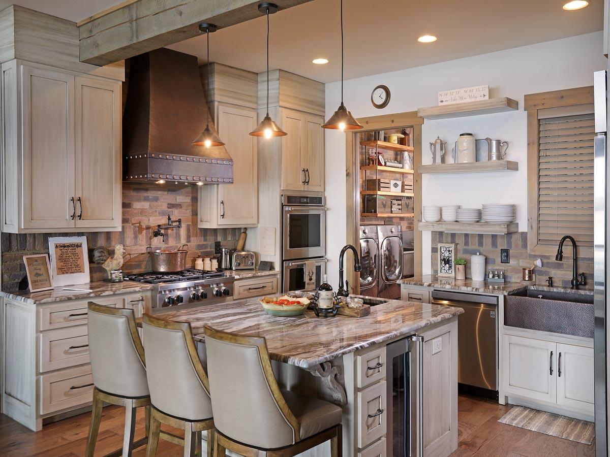 Kitchen with large island, copper range hood, brick backsplash, farmhouse sink, and open shelving.