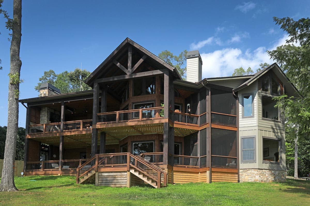 House plan exterior with multiple levels of decks, a screened porch, large gabled roofline, and stone accents.