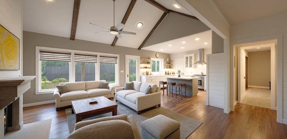 Spacious, open-plan living space with a vaulted ceiling. It includes a seating area, fireplace, and flows into a kitchen with a breakfast bar.