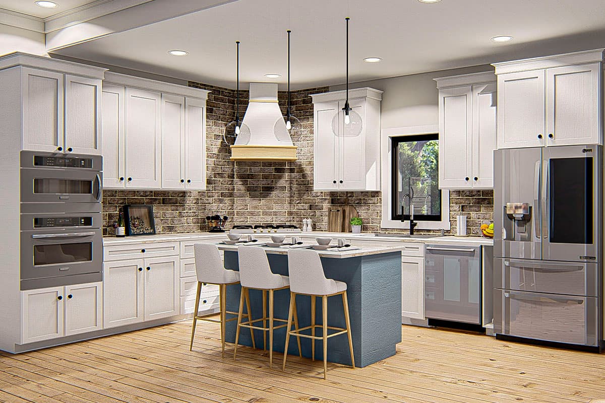 Kitchen interior with white cabinetry, island with seating, stainless steel appliances, and brick backsplash.
