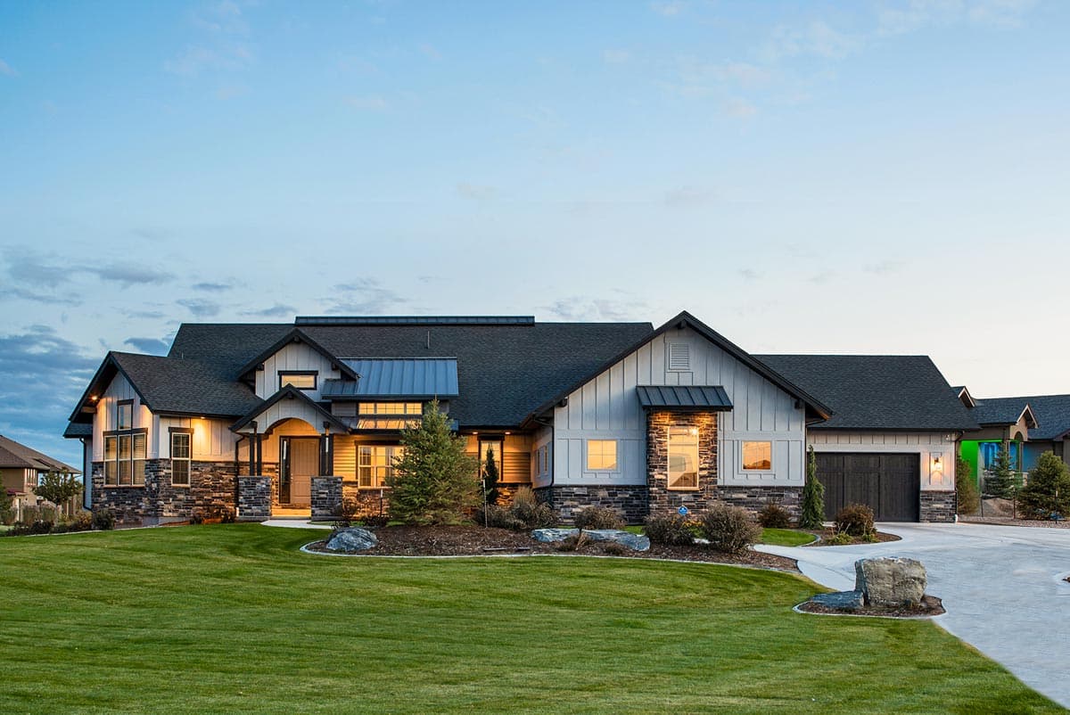 House plan exterior with board and batten siding, multiple gables, and a mix of stone and metal accents. Features an attached garage and front porch.