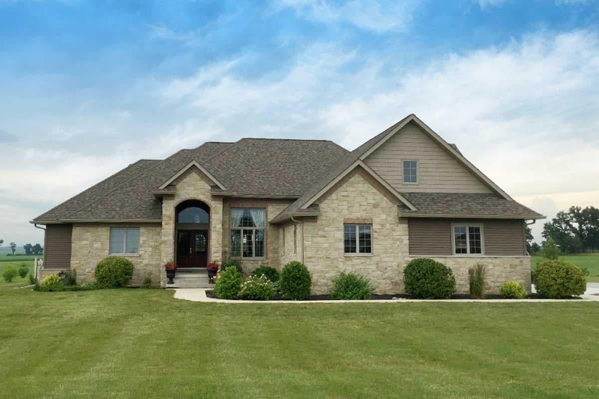 House plan exterior featuring stone and siding, arched entry, multiple gables, and a prominent roofline.