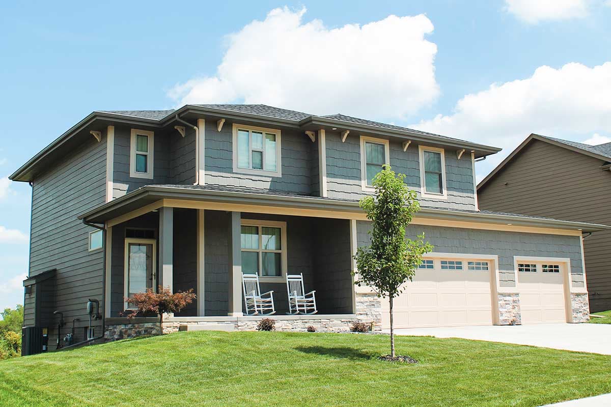 Two-story Modern Farmhouse plan with covered front porch, stone accents, gabled dormers, and a three-car garage.